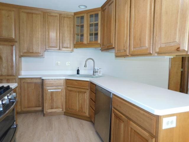 711 Glendale Ave, Rockford, IL 61108 - kitchen featuring appliances with stainless steel finishes, light countertops, light wood finished floors, brown cabinetry, and glass insert cabinets
