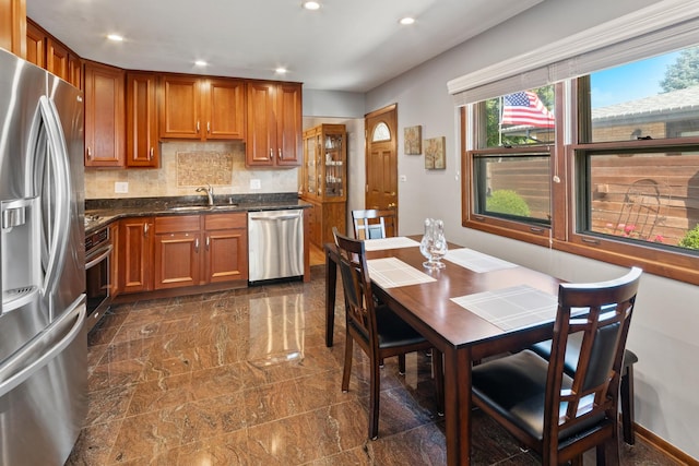 6955 N Dowagiac Ave, Chicago, IL 60646 - kitchen with appliances with stainless steel finishes, brown cabinetry, recessed lighting, decorative backsplash, and dark stone countertops