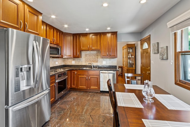6955 N Dowagiac Ave, Chicago, IL 60646 - kitchen featuring stainless steel appliances, brown cabinets, recessed lighting, tasteful backsplash, and dark stone countertops