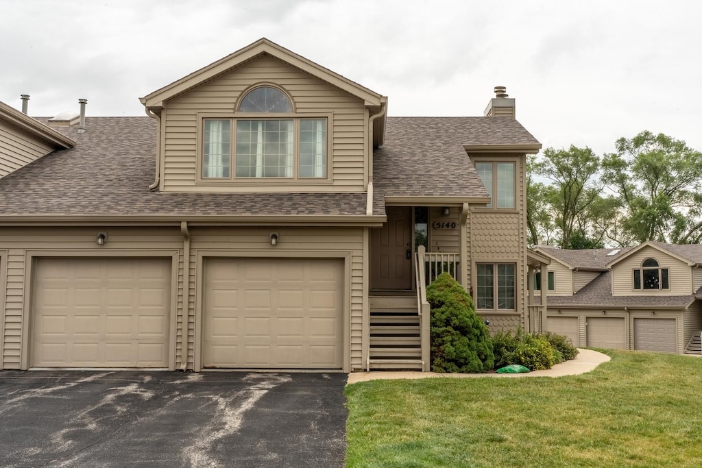 5140 Morning Glory Ln Unit 0, Loves Park, IL 61111 - view of front of house featuring a shingled roof, asphalt driveway, a chimney, and a front lawn