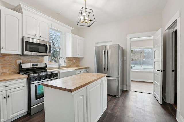 7959 S Saginaw Ave, Chicago, IL 60617 - kitchen featuring appliances with stainless steel finishes, wood counters, a center island, a chandelier, and white cabinetry
