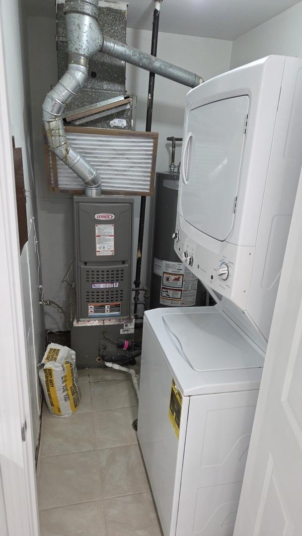 1303 Kingsbury Dr Unit A, Hanover Park, IL 60133 - washroom featuring stacked washing machine and dryer, gas water heater, and light tile patterned floors
