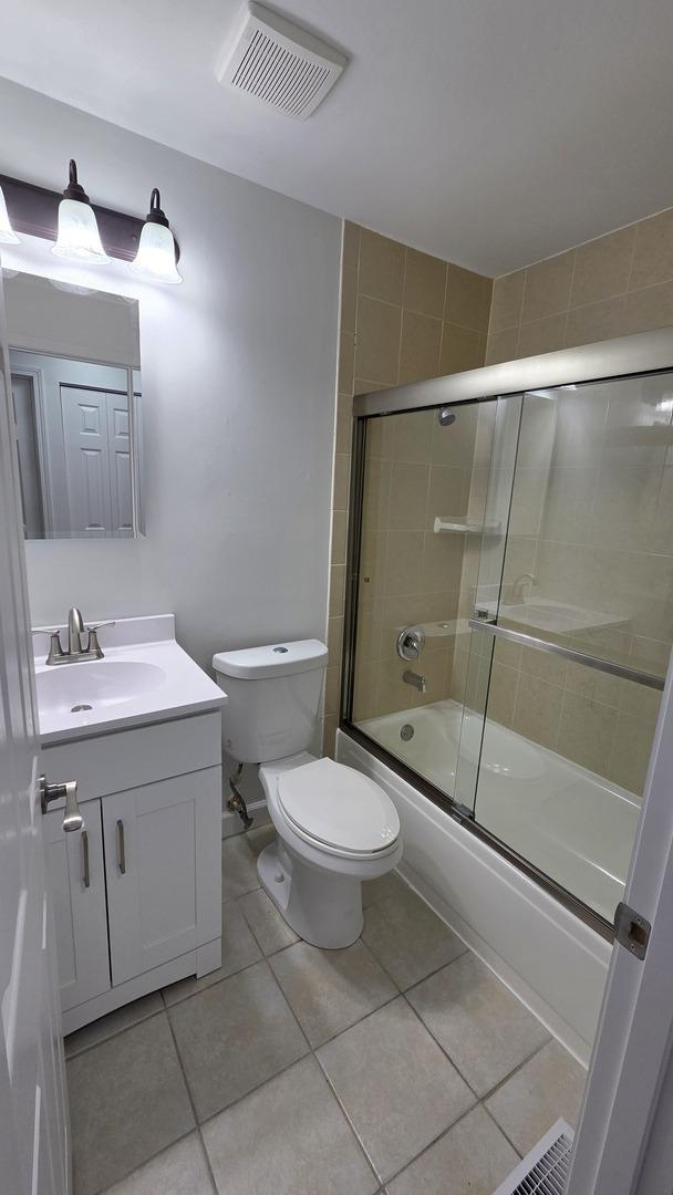 1303 Kingsbury Dr Unit A, Hanover Park, IL 60133 - bathroom with vanity, bath / shower combo with glass door, and tile patterned flooring