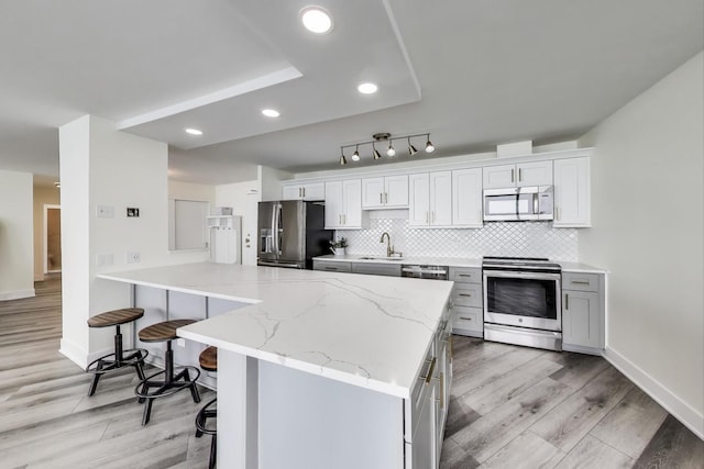 940 W Glenlake Ave Unit 19C, Chicago, IL 60660 - kitchen with stainless steel appliances, a breakfast bar area, light wood-style floors, backsplash, and light stone countertops