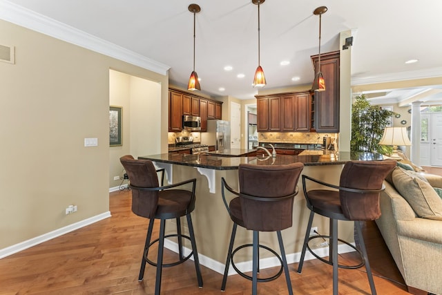 9 Aztec Ct, South Barrington, IL 60010 - kitchen with appliances with stainless steel finishes, a peninsula, decorative backsplash, crown molding, and a kitchen bar