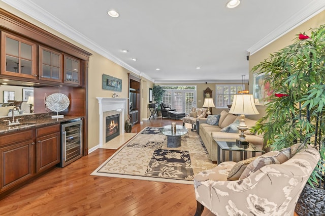 9 Aztec Ct, South Barrington, IL 60010 - living area with wine cooler, light wood finished floors, ornamental molding, a high end fireplace, and recessed lighting
