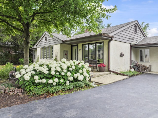 216 Hickory Ct, Northbrook, IL 60062 - view of front of house with stucco siding, a chimney, and a shingled roof