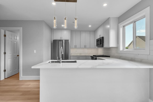 24642 George Washington Dr, Plainfield, IL 60544 - kitchen featuring appliances with stainless steel finishes, light wood finished floors, tasteful backsplash, recessed lighting, and a peninsula