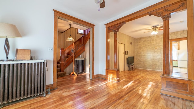 10747 S S Ave H, Chicago, IL 60617 - unfurnished living room featuring ornate columns, ceiling fan, hardwood / wood-style flooring, stairs, and radiator heating unit