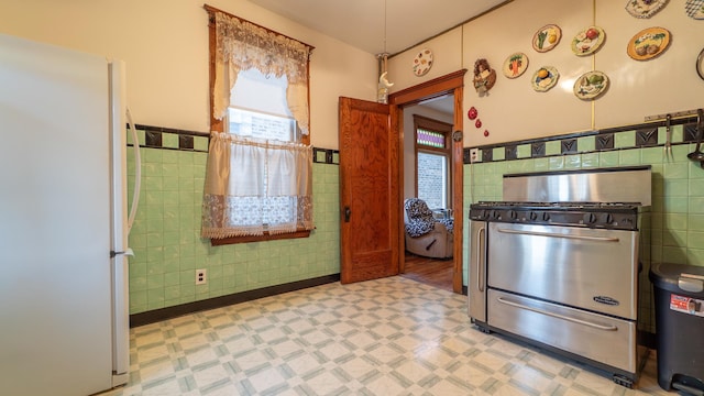 10747 S S Ave H, Chicago, IL 60617 - kitchen with freestanding refrigerator, stainless steel gas range, tile walls, light flooring, and wainscoting