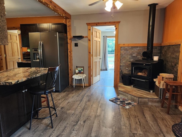 3100 W Brooke Ave, Waukegan, IL 60087 - kitchen featuring stainless steel fridge, a wood stove, wood finished floors, ceiling fan, and light stone countertops