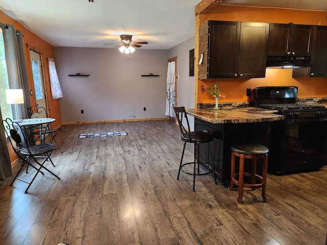 3100 W Brooke Ave, Waukegan, IL 60087 - kitchen with black range with gas cooktop, under cabinet range hood, a kitchen bar, dark wood-type flooring, and ceiling fan