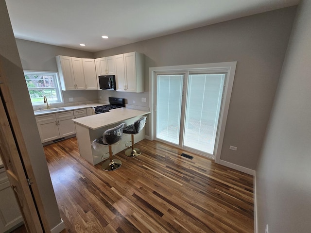 327 Lincoln Ave, Woodstock, IL 60098 - kitchen with black appliances, a peninsula, dark wood-style flooring, white cabinetry, and recessed lighting