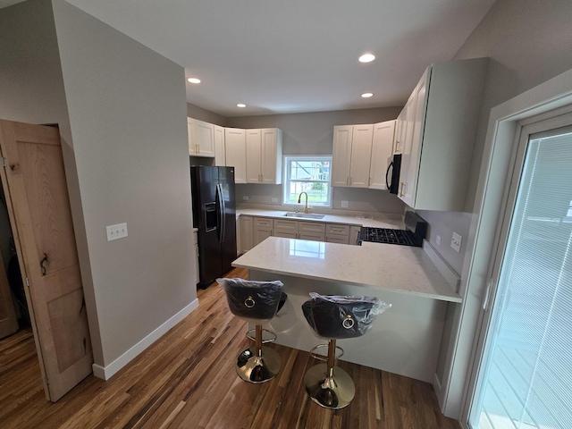 327 Lincoln Ave, Woodstock, IL 60098 - kitchen featuring black appliances, a peninsula, wood finished floors, white cabinets, and recessed lighting