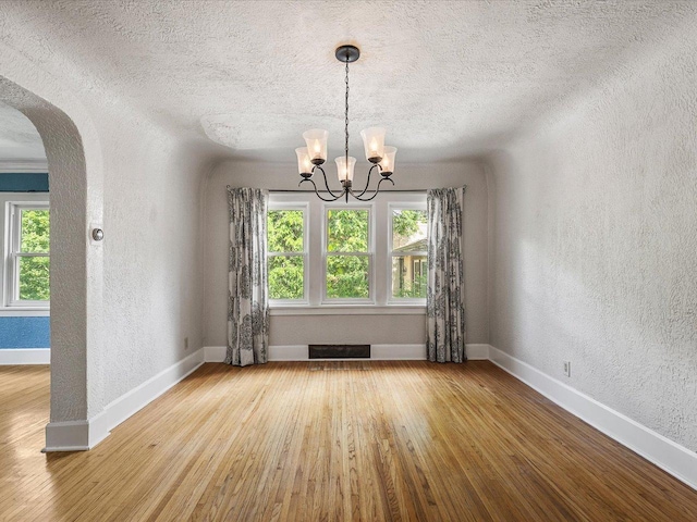 1639 Arlington Ave, Rockford, IL 61107 - unfurnished dining area featuring a textured wall, arched walkways, plenty of natural light, wood-type flooring, and a chandelier