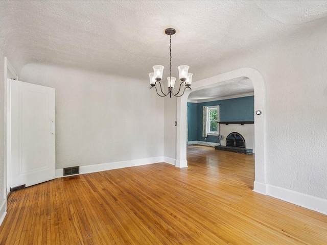 1639 Arlington Ave, Rockford, IL 61107 - spare room featuring a textured ceiling, wood finished floors, arched walkways, and a chandelier