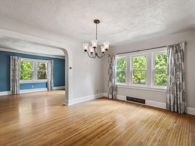1639 Arlington Ave, Rockford, IL 61107 - empty room with light wood-style floors, arched walkways, a textured ceiling, a chandelier, and a baseboard heating unit