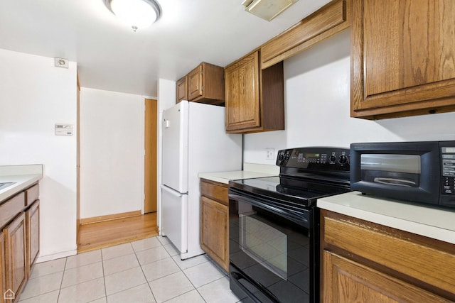 1121 S Plymouth Ct Unit A, Chicago, IL 60605 - kitchen featuring black appliances, light tile patterned floors, brown cabinetry, and light countertops