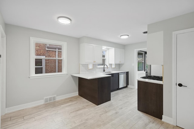 5406 N Mulligan Ave, Chicago, IL 60630 - kitchen with stainless steel appliances, light countertops, white cabinetry, light wood-style floors, and a peninsula