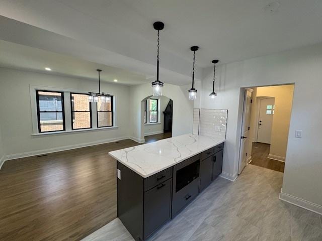 3512 Woodside Ave, Brookfield, IL 60513 - kitchen featuring arched walkways, a peninsula, decorative light fixtures, dark cabinetry, and light stone countertops