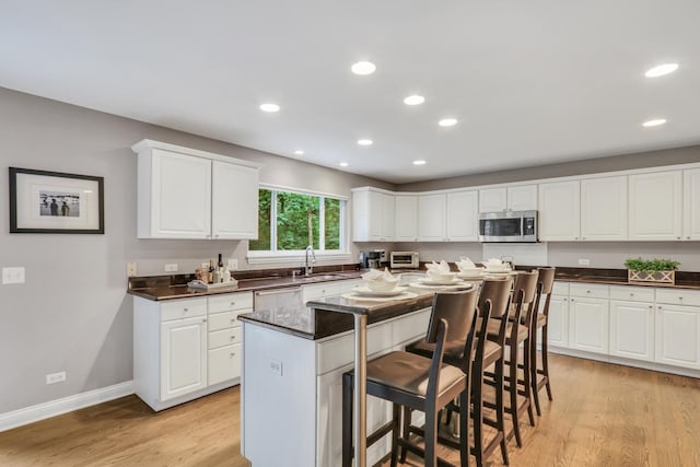 7509 Bittersweet Dr, Gurnee, IL 60031 - kitchen with stainless steel appliances, a kitchen bar, a kitchen island, light wood-type flooring, and recessed lighting