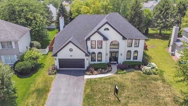 2011 Gleneagle Dr, Plainfield, IL 60586 - french country home featuring asphalt driveway, a chimney, roof with shingles, a front yard, and a garage