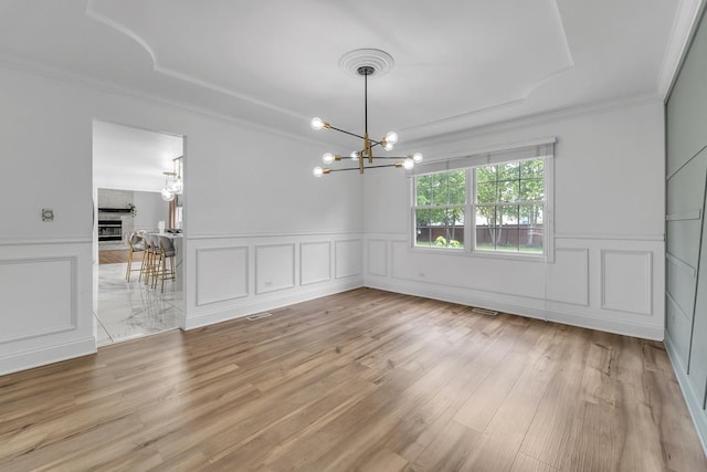2011 Gleneagle Dr, Plainfield, IL 60586 - unfurnished dining area featuring a chandelier, a decorative wall, crown molding, light wood-style flooring, and a wainscoted wall
