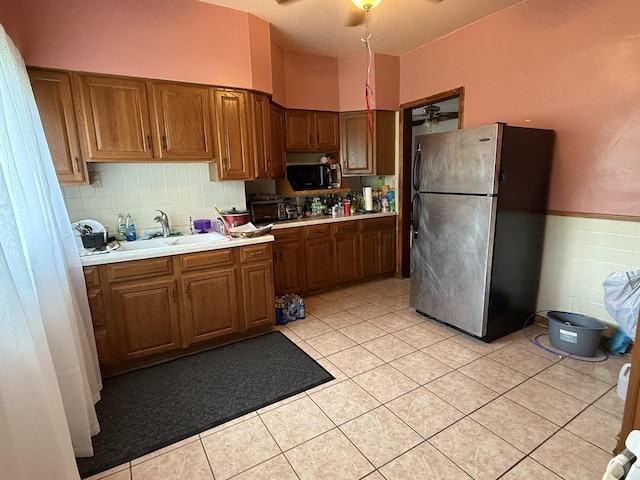 1250 Corbin St, Rockford, IL 61102 - kitchen featuring freestanding refrigerator, black microwave, light countertops, brown cabinetry, and light tile patterned flooring
