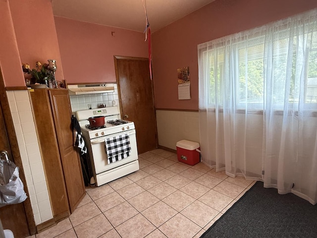 1250 Corbin St, Rockford, IL 61102 - kitchen with white range with gas stovetop, plenty of natural light, light tile patterned floors, and under cabinet range hood