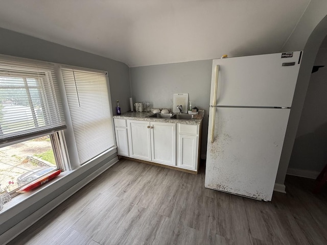 1250 Corbin St, Rockford, IL 61102 - kitchen featuring freestanding refrigerator, wood finished floors, lofted ceiling, white cabinets, and arched walkways
