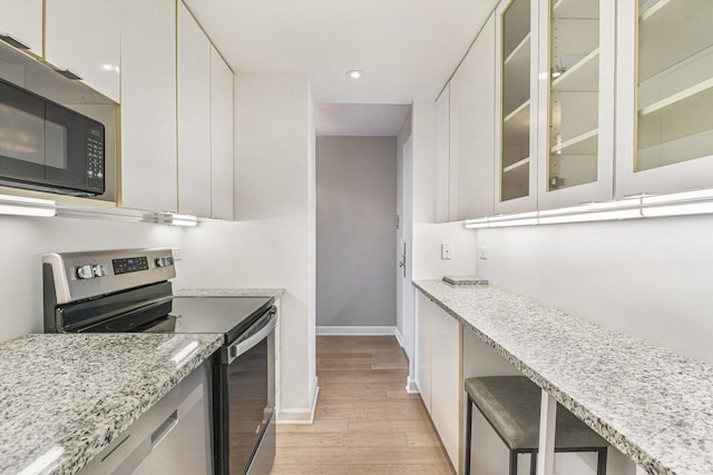1550 N Lake Shore Dr Unit 2A, Chicago, IL 60610 - kitchen with electric range, black microwave, light wood finished floors, white cabinetry, and glass insert cabinets