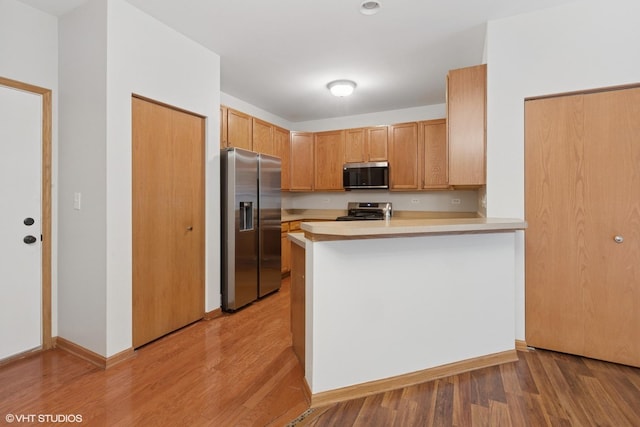 133 Springbrook Trl S, Oswego, IL 60543 - kitchen with stainless steel appliances, light countertops, light wood-style floors, and a peninsula