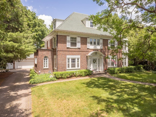 1286 W Stephenson St, Freeport, IL 61032 - colonial house featuring brick siding, decorative driveway, a front yard, a garage, and an outdoor structure