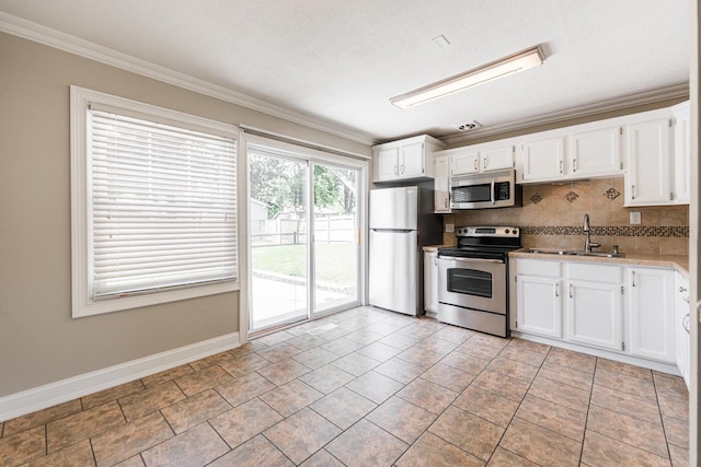 1614 E Dresser Rd, Dekalb, IL 60115 - kitchen with appliances with stainless steel finishes, ornamental molding, tasteful backsplash, white cabinets, and light countertops