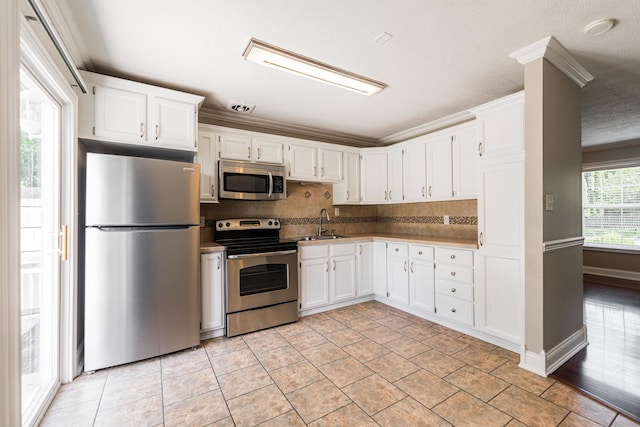 1614 E Dresser Rd, Dekalb, IL 60115 - kitchen featuring stainless steel appliances, white cabinets, backsplash, and ornamental molding