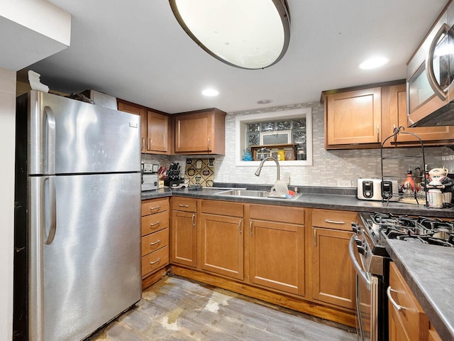385 E Irving Park Rd, Streamwood, IL 60107 - kitchen featuring stainless steel appliances, brown cabinets, decorative backsplash, light wood-style floors, and dark countertops