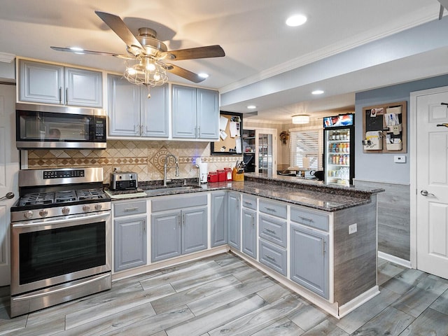 385 E Irving Park Rd, Streamwood, IL 60107 - kitchen featuring stainless steel appliances, a peninsula, crown molding, a ceiling fan, and dark stone counters