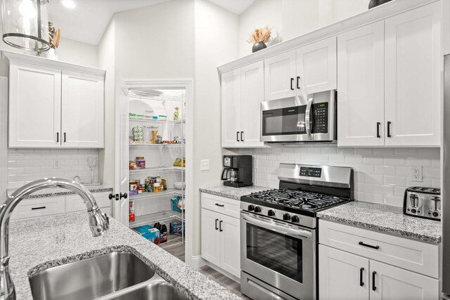 2621 Shale Rd, Normal, IL 61761 - kitchen with stainless steel appliances, decorative backsplash, white cabinets, and light stone countertops