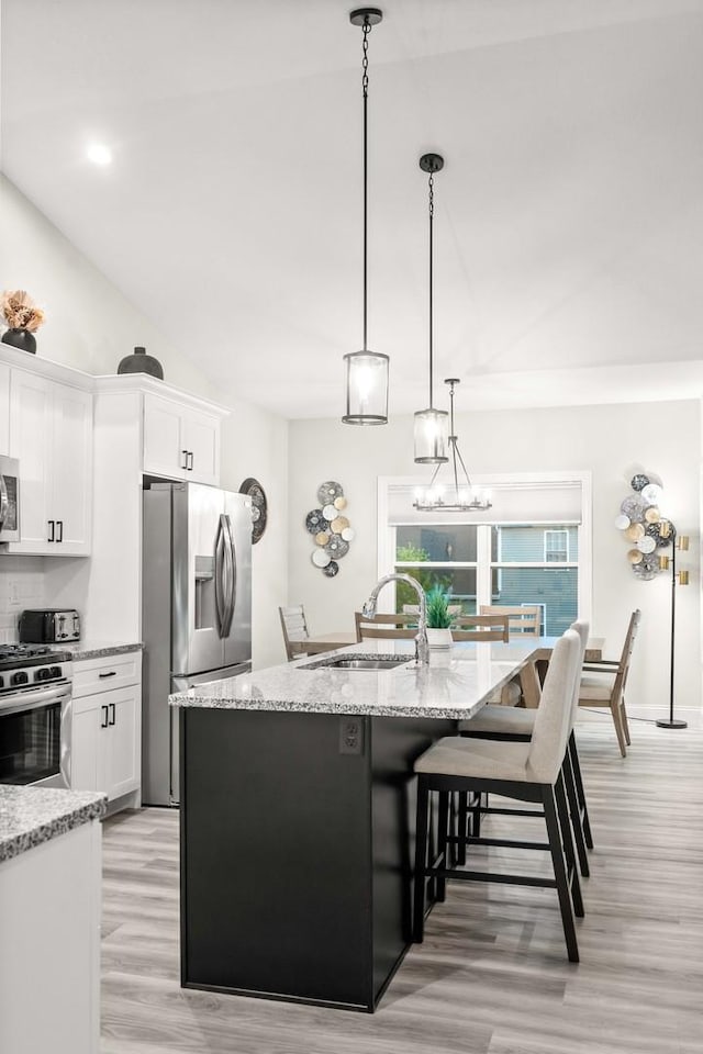 2621 Shale Rd, Normal, IL 61761 - kitchen featuring appliances with stainless steel finishes, white cabinets, an island with sink, light wood-type flooring, and vaulted ceiling