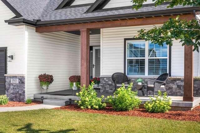 2621 Shale Rd, Normal, IL 61761 - view of exterior entry featuring covered porch, a shingled roof, stone siding, and a yard