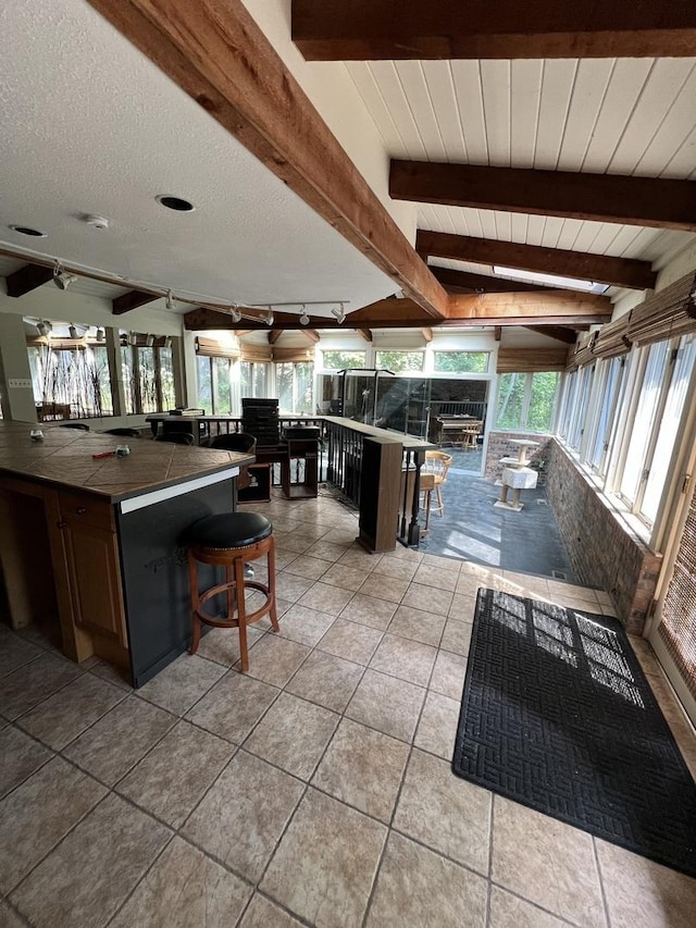 16612 S Catawba Rd, Homer Glen, IL 60491 - kitchen with beamed ceiling, tile counters, track lighting, light tile patterned floors, and a kitchen breakfast bar