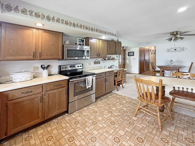 610 S 2nd Ave, Forreston, IL 61030 - kitchen featuring appliances with stainless steel finishes, light countertops, a ceiling fan, a textured ceiling, and brown cabinets