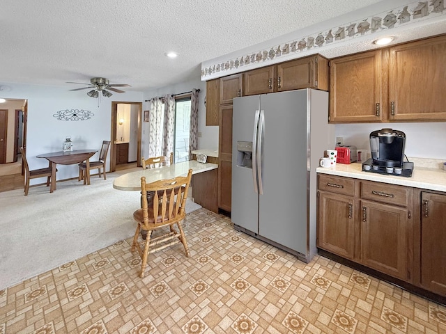 610 S 2nd Ave, Forreston, IL 61030 - kitchen featuring stainless steel refrigerator with ice dispenser, light countertops, ceiling fan, a textured ceiling, and brown cabinets