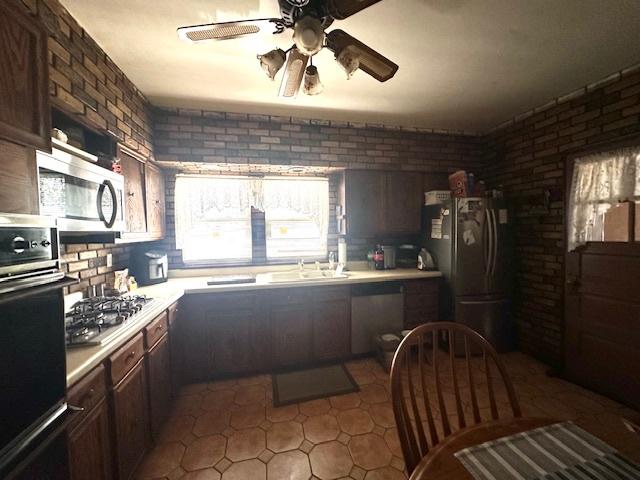 4540 N Menard Ave, Chicago, IL 60630 - kitchen with stainless steel appliances, a ceiling fan, light countertops, built in desk, and brick wall