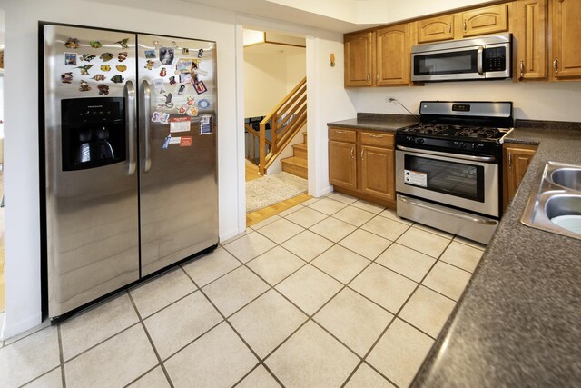 1065 Irwin Ave, Des Plaines, IL 60018 - kitchen with appliances with stainless steel finishes, dark countertops, light tile patterned floors, and brown cabinetry