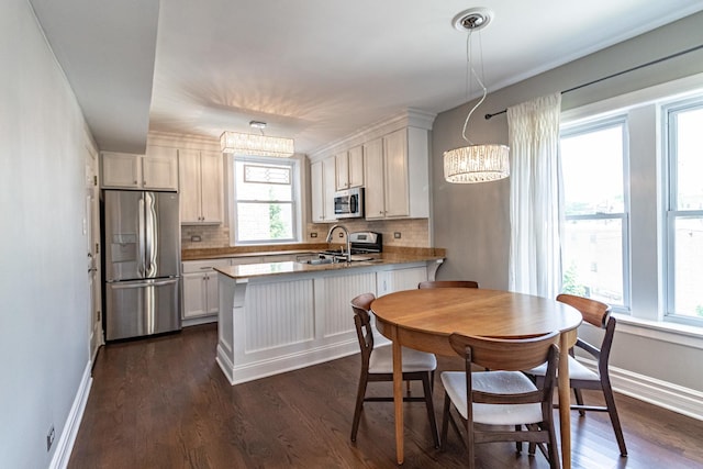 5952 N Paulina St Unit 2N, Chicago, IL 60660 - kitchen with stainless steel appliances, a chandelier, a peninsula, tasteful backsplash, and dark wood-style floors