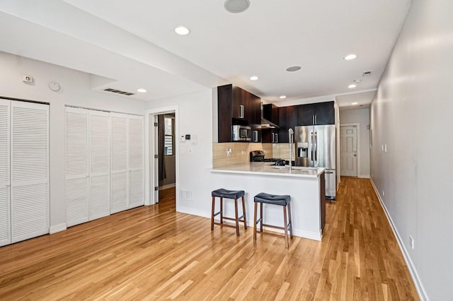 2423 W Augusta Blvd Unit 1, Chicago, IL 60622 - kitchen featuring stainless steel appliances, a breakfast bar area, decorative backsplash, light wood finished floors, and light countertops