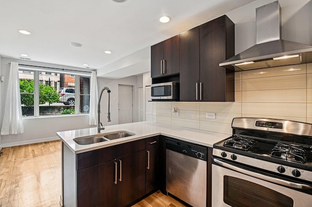 2423 W Augusta Blvd Unit 1, Chicago, IL 60622 - kitchen featuring stainless steel appliances, wall chimney range hood, a peninsula, light wood-type flooring, and light countertops