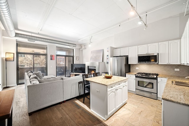 1301 W Madison St Unit 207, Chicago, IL 60607 - kitchen featuring appliances with stainless steel finishes, track lighting, decorative backsplash, and white cabinets