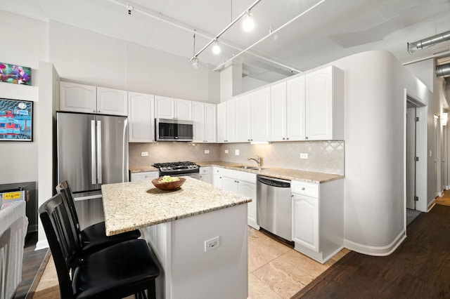 1301 W Madison St Unit 207, Chicago, IL 60607 - kitchen with stainless steel appliances, light stone counters, rail lighting, and a kitchen island